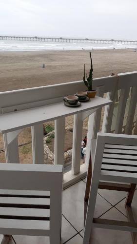 einen weißen Tisch und einen Stuhl mit Blick auf den Strand in der Unterkunft ArenaNorte in Chiclayo