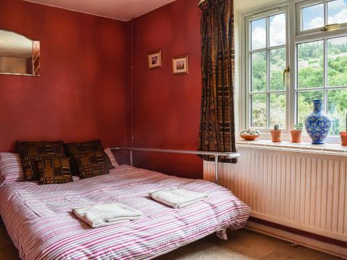 a bedroom with a bed with two pillows and a window at The Cottage in Blakeney