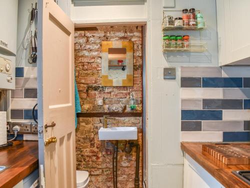 a bathroom with a brick wall and a sink at The Epple Bay Retreat in Birchington