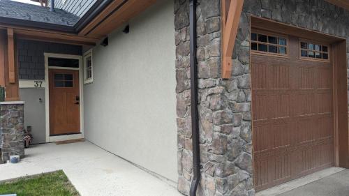 garaje con puerta de madera y pared de piedra en Echo Landing #37 condo, en Sun Peaks