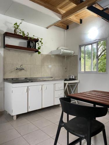 una cocina con armarios blancos y una mesa con una silla en Complejo Las Flores - Lugar campestre a 5 minutos de Termas Chajarí en Chajarí
