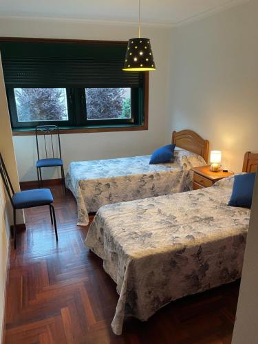Un dormitorio con dos camas y una silla y una ventana. en Cangas Piso Completo, en Cangas de Morrazo