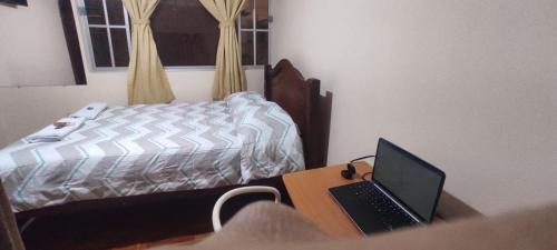 1 dormitorio con cama y escritorio con ordenador portátil en Estefanyyyy, en Latacunga