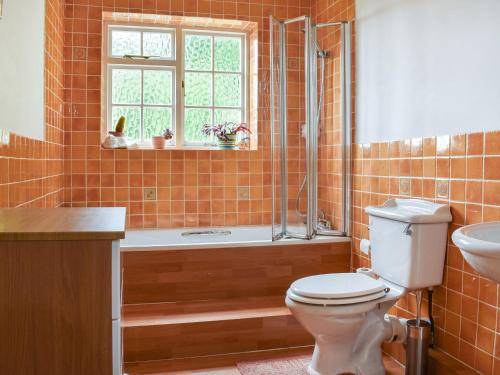 a bathroom with a tub and a toilet and a sink at The Cottage in Blakeney