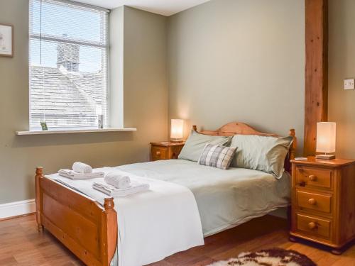 a bedroom with a bed with two night stands and a window at St, Georges Cottage in Holmfirth