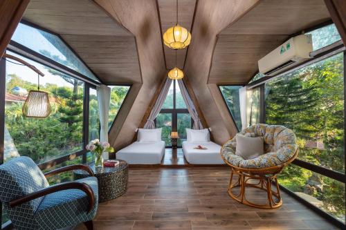 una habitación con ventanas y sillas en una casa en un árbol en Bai Dinh Garden Resort & Spa, en Ninh Binh