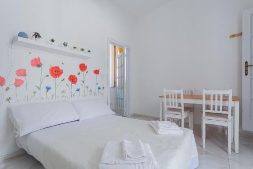 ein Schlafzimmer mit einem Bett mit roten Blumen an der Wand in der Unterkunft Casa Bianca bnb Big Terrace 10min Airport, Beach in Bitonto