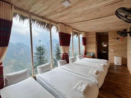 a bedroom with two beds and a large window at Mã Pì Lèng EcoLodge in Mèo Vạc