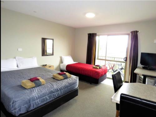 a hotel room with two beds and a desk and a television at Palmcourt Motel in Westport