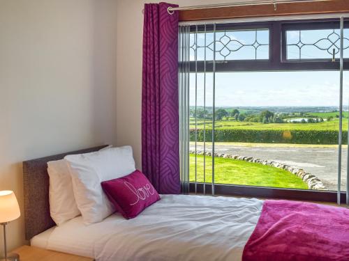a bedroom with a bed and a window with purple curtains at Lowesmuir Cottage in Cumnock