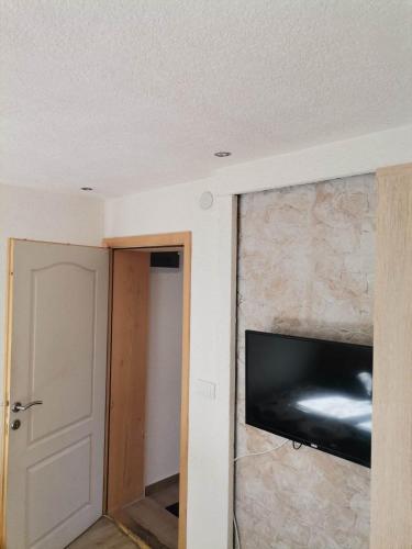 a room with a stone wall with a flat screen tv at Golubović Apartments in Žabljak