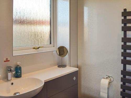 a bathroom with a sink and a window at Lowesmuir Cottage in Cumnock