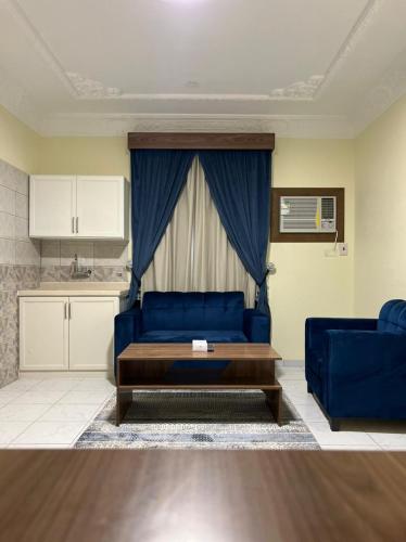 a living room with a blue couch and a kitchen at ريف الزهور للشقق الفندقيه in Dammam