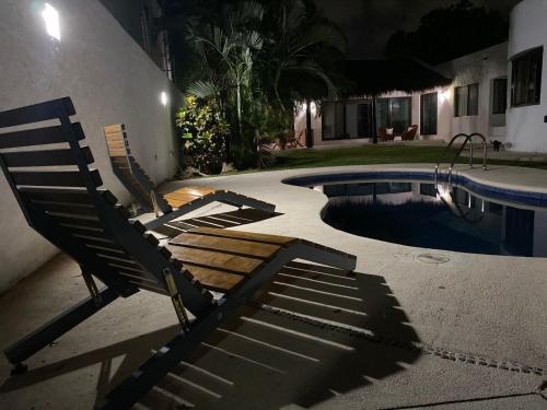 two chairs sitting next to a swimming pool at night at Casa Iola in Cancún