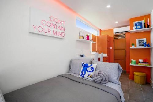 a bedroom with a bed and a sign that reads dont complain your mind at Orange Container @EADO Juice Box in Houston