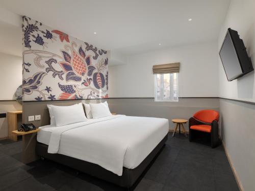a bedroom with a white bed and a red chair at Swiss-Belinn Medan in Medan