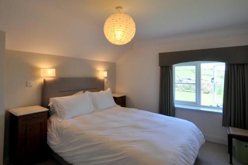 a bedroom with a white bed and a window at Culverwells in Axminster