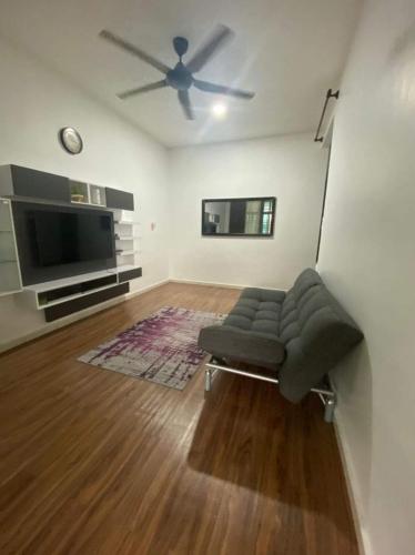 sala de estar con sofá y TV de pantalla plana en Amani Homestay en Kuantan