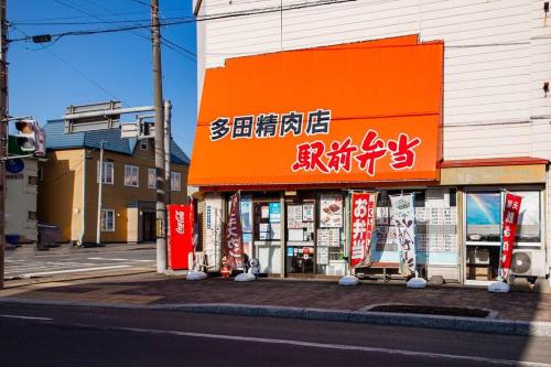 a store with an orange sign on the side of a street at The Landscape in Kami-furano