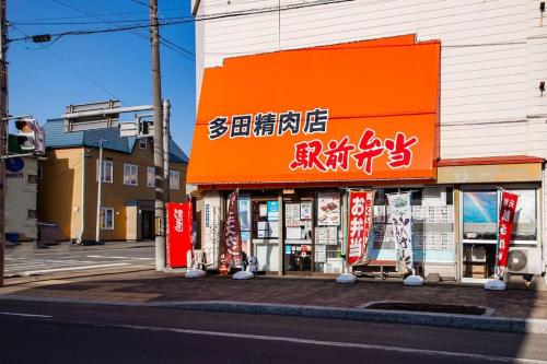 a store with an orange sign on the side of a street at The Landscape in Kami-furano