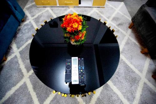 a table with a remote control and a vase of flowers at Appartement meublé in Douala
