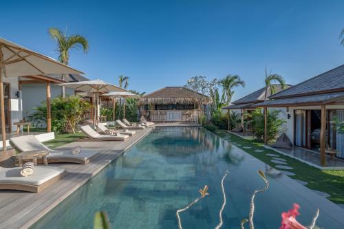 a pool at a villa with lounge chairs at EHOA BALI Nyanyi Boutique Hotel - In front of entrance to NUANU in Tanah Lot