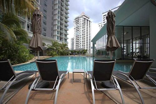 a pool with chairs and a table and some buildings at OOAK SUITES AT MONT KIARA KUALA LUMPUR in Kuala Lumpur