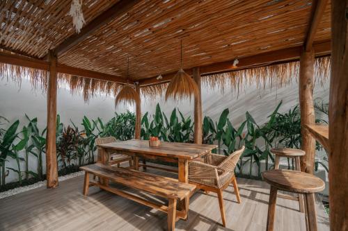 a wooden table and chairs on a patio with a wall of plants at EHOA NYANYI BEACH Boutique Hotel - In front of entrance to NUANU in Tanah Lot