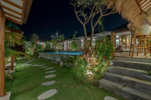 a garden with a swimming pool at night at EHOA NYANYI BEACH Boutique Hotel - In front of entrance to NUANU in Tanah Lot
