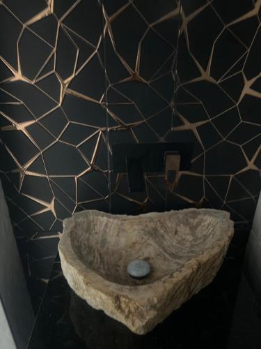 Luxury Holiday House في فالنسيا: حمام مع وعاء حجري على جدار أسود