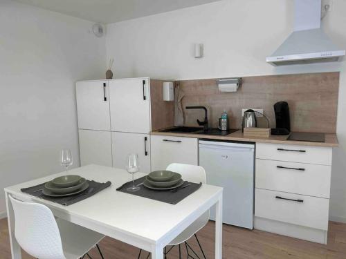 une cuisine blanche avec une table et des chaises blanches dans l'établissement Appart le 102 Netflix -parking gratuit, à Jasseron