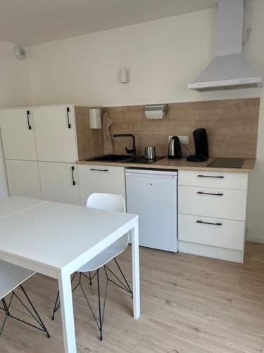 - une cuisine avec une table et une table et des chaises blanches dans l'établissement Appart le 102 Netflix -parking gratuit, à Jasseron