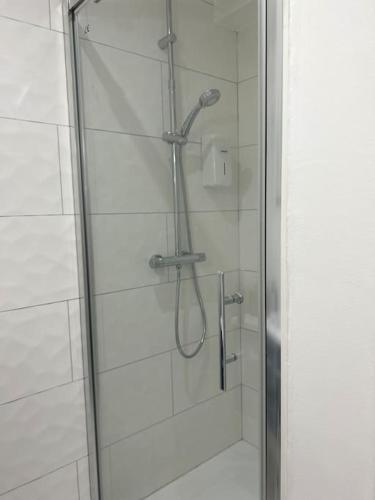 d'une douche avec une porte en verre et un pommeau de douche. dans l'établissement Appart le 102 Netflix -parking gratuit, à Jasseron