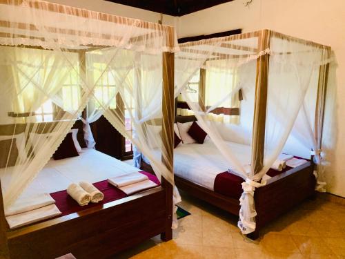 a bedroom with two beds with mosquito nets at Sinhagiri Villa in Sigiriya