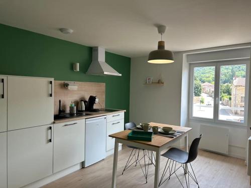 une cuisine avec des appareils blancs et une table avec des chaises dans l'établissement Appart le 201 Jasseron, à Jasseron
