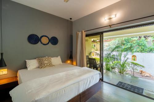 a bedroom with a bed and a large window at The Banyan Soul in Anjuna