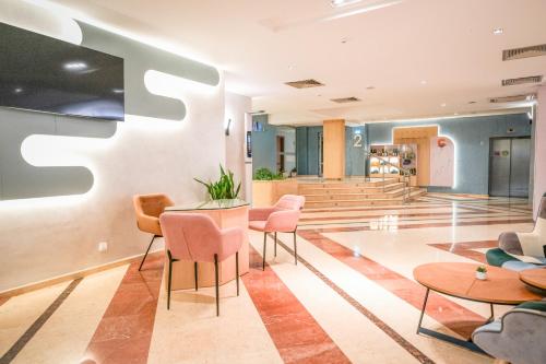 vestíbulo de un edificio con mesas y sillas rosas en Calimera Ralitsa Superior Hotel - Ultra All Inclusive plus Aquapark en Albena