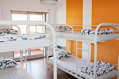 a room with three bunk beds and a window at Villa do Sol Carcavelos Beach House in Carcavelos