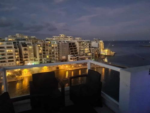 a balcony with two chairs and a view of the ocean at St Julians Bay Sea Front Apartments in St Julian's