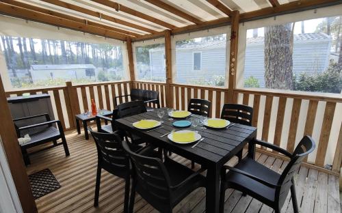 een zwarte tafel en stoelen op een afgeschermde veranda bij les Dunes de Contis in Saint-Julien-en-Born