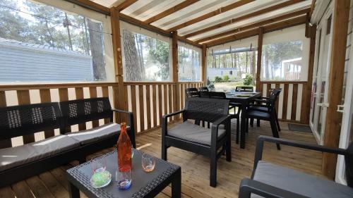une véranda avec des chaises, des tables et des fenêtres. dans l'établissement les Dunes de Contis, à Saint-Julien-en-Born