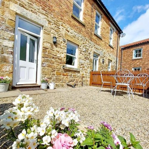 a patio with a table and chairs in front of a building at Serendipity cottage in Castleton