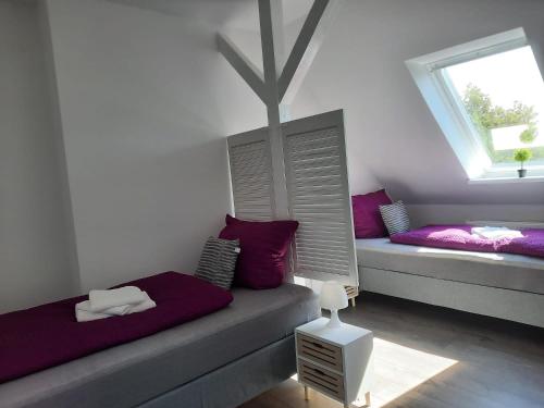 Pokój z 2 łóżkami z fioletowymi poduszkami i oknem w obiekcie Villa Mariensiel II w mieście Sande