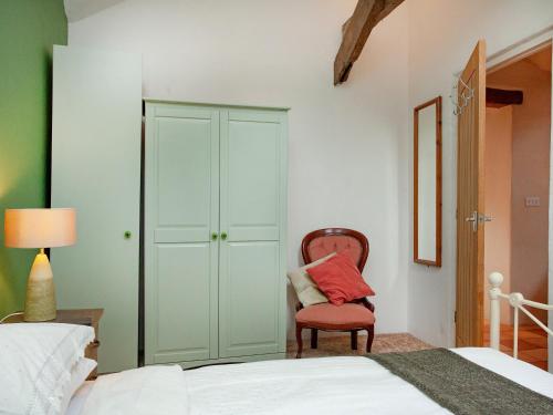 a bedroom with a bed and a red chair at Lifton Hall - The Barn in Lifton