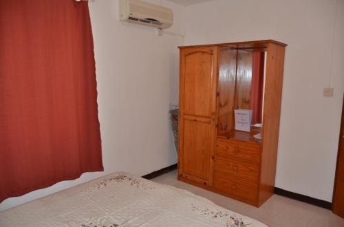 a bedroom with a wooden cabinet and a bed at Les Gentilhommieres Guest House in Trou aux Biches