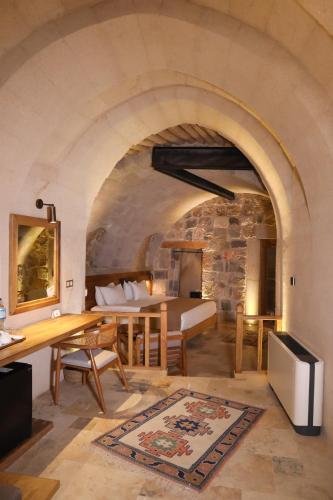 a living room with a table and a bed in a room at Kappadoks Cave Hotel in Uchisar
