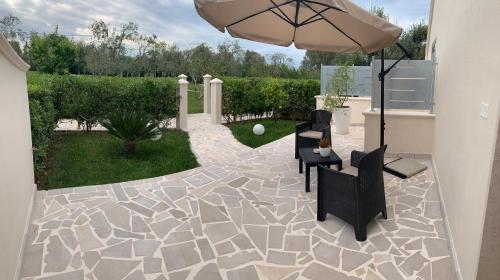a patio with two chairs and an umbrella at Tenuta Verdolivo in Ostuni