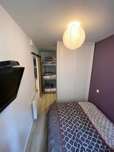 - une petite chambre avec un lit et un lustre dans l'établissement Très bel appartement Cauterets centre 6 places, à Cauterets