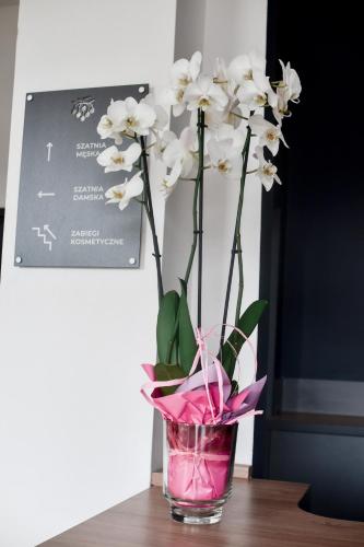 a vase filled with white flowers sitting on a table at Jarzębinowy Resort & SPA in Braniewo