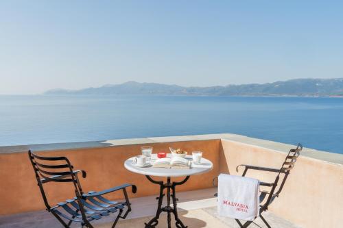 a table and chairs on a balcony overlooking the water at Bastione Malvasia Hotel (ex New Malvasia) in Monemvasia